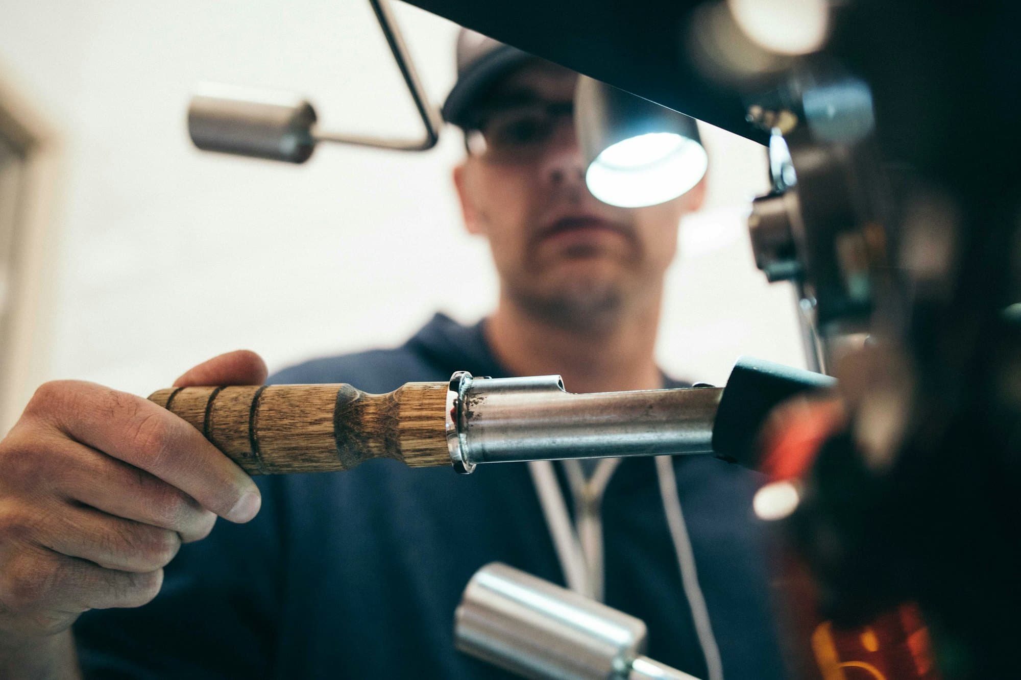 Main d'artisan manipulant un outil de précision sous une lampe d'atelier.